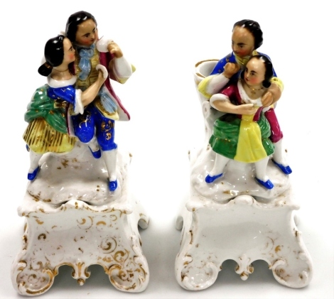 A pair of continental porcelain figure groups, each with spill vase back depicting two figure in embrace, one with fans, the bases with gilt detailing (AF), 22cm high.