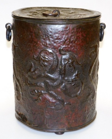 An Arts and Crafts coal bucket, in an ebonised copper finish design of heads of dragons, with two swing handles, on three bun feet, 34cm high, 33cm diameter. (AF)