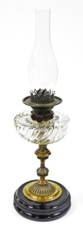 A 19thC brass oil lamp, with wrythen glass reservoir, on an black glazed circular foot, 61cm high.