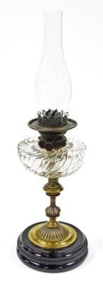 A 19thC brass oil lamp, with wrythen glass reservoir, on an black glazed circular foot, 61cm high.