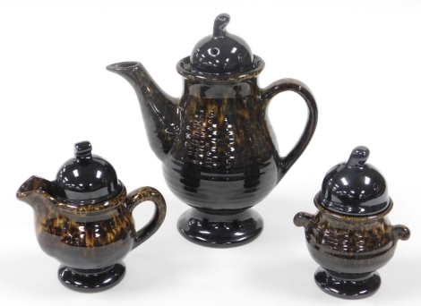 A stoneware coffee set, comprising coffee pot, milk jug and sugar bowl, each with a brown mottled finish, unmarked.