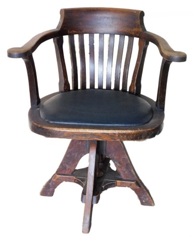 A oak swivel captain's chair, with lath back and black leather inset seat.