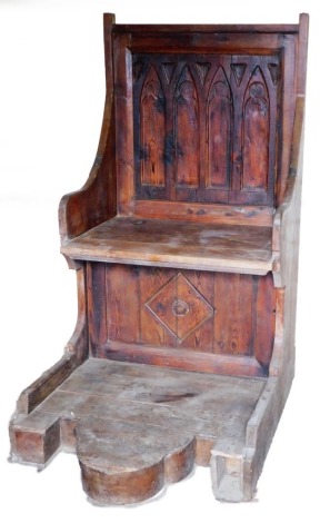A stained pine Gothic style throne chair, the two seat back with carved detailing, on a later base, 153cm high, 83cm wide, 110cm deep.