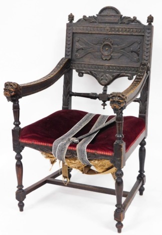 A 19thC Gothic carved oak hall chair, with a panel back and lion mask handles, on red draylon seat, with H frame base, 106cm high, 63cm wide, 60cm deep.
