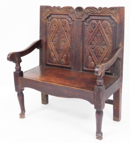 A late 19thC oak settle, with two seat panel back, with flowers and scroll detailing, 107cm high, 92cm wide, 55cm deep.
