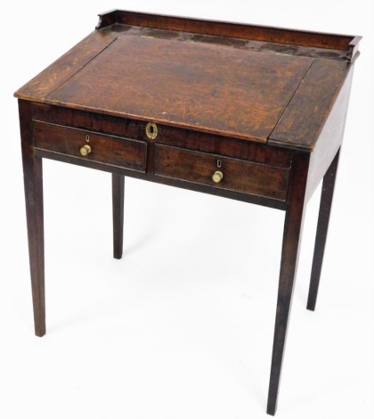 An early 19thC oak clerk's desk, with tray top central lift lid section above two drawers with brass escuteons, on taper legs, 91cm high, 78cm wide, 55cm deep.