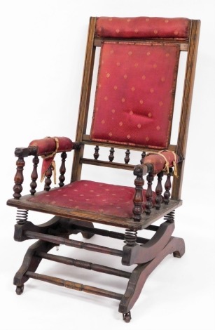 A Victorian turned walnut rocking chair, with red upholstery, on rocker base, 105cm high, 54cm wide, 62cm deep.