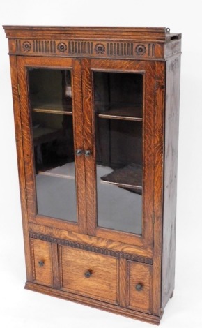 An oak wall hanging cabinet, the top cornice with flower and stem design above two astragal glazed doors, and three cupboard section base, 132cm high, 72cm wide, 25cm deep.