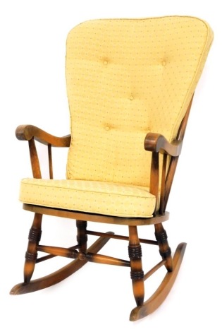 An Ercol style rocking chair, with yellow upholstered cushions, light elm, 102cm high, 53cm wide, 55cm deep. The upholstery in this lot does not comply with the 1988 (Fire & Fire Furnishing) Regulations, unless sold to a known exporter or upholsterer it 