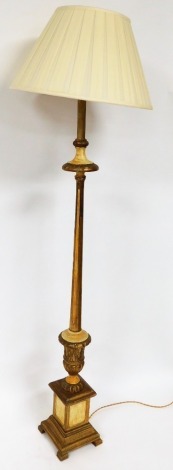 A gilt standard lamp, in gold with cream detailing, on a stepped base with cream shade, 172cm high.