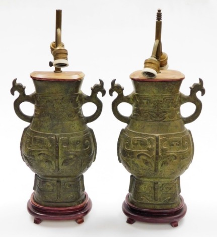 A pair of Eastern bronze twin sconce table lamps, each with relief decoration in archaic style, on stepped base, 56cm high. (AF)