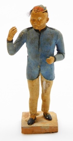 A 19thC Chinese terracotta figure of a standing male, with one arm raised, wearing a blue tunic and skull cap, standing on a square plinth base, 15.5cm high.