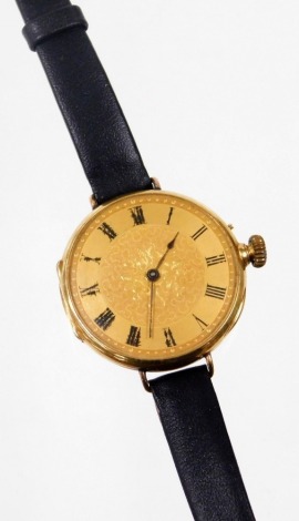 A wristwatch, the circular dial with Roman numerals and central floral detailing, with black hands and bezel wind, in a yellow metal case, unmarked, opening to reveal internal inscription To Darling Marjorie Dearest and Best of Women On Her Wedding Day By