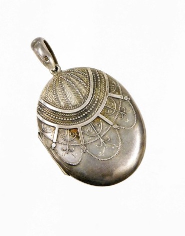 A Victorian silver oval locket, the front with heavily applied scroll and foliate detailing, opening to reveal two portraits, Birmingham 1876, 5cm high, 17.6g.