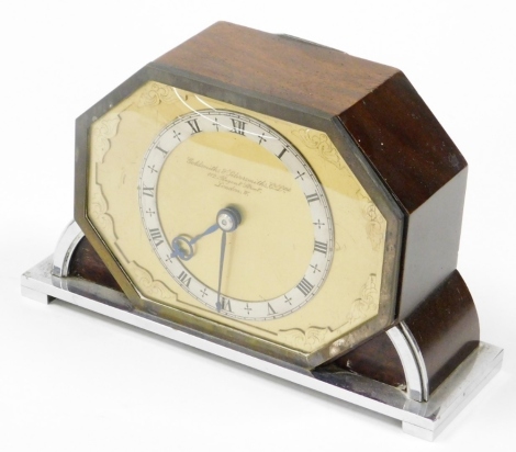 A Goldsmiths and Silversmiths Company Art Deco mantel clock, with octagonal front shield on gold coloured backing with silver border and blue hands, marked 112 Regent Street, London, in a wooden case with chrome fittings, 12cm high, 18cm wide.