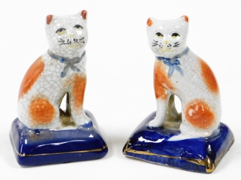 Two Staffordshire style figures of cats, each seated on blue pillow, 11cm high.
