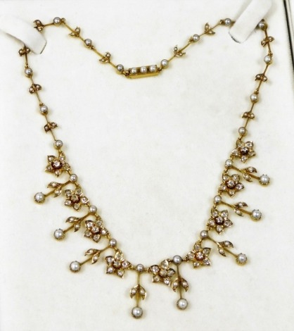 A pearl and diamond necklace, the floral design diamond set five petal flowers, with cultured pearl, leaf drops and breaks, each diamond flower, 1cm wide, on a yellow metal necklet, unmarked, possibly 18ct, 49cm long overall, 24.5g, all in, boxed.