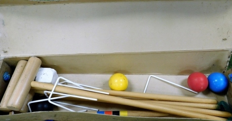 A cased croquet set, in a cardboard sleeve with wooden ends, comprising four mallets, stakes, and various balls, unmarked.