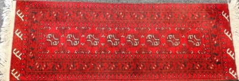 A Bokhara design rug with red ground, 52cm x 146cm.