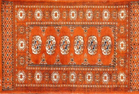 A Bokhara design rug with orange ground, 62cm x 96cm.