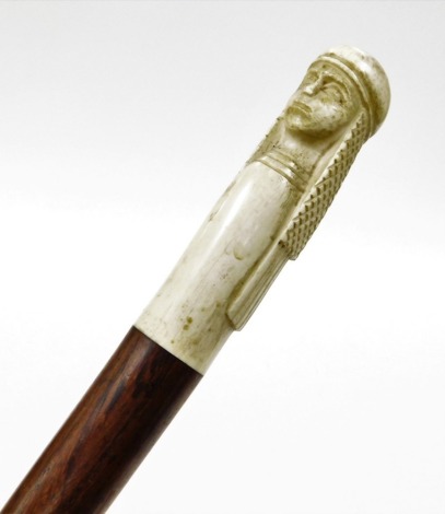 An early 20thC turned rosewood walking cane, with a carved ivory finial in the form of an Arab wearing headdress.