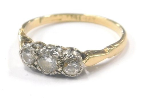 A diamond three stone dress ring, with three illusion set round brilliant cut diamonds, approx 0.15ct and two 0.10ct, in a platinum claw setting, with pierced design shoulders on a yellow metal band, stamped 18ct plat, ring size M½, 2.1g all in.