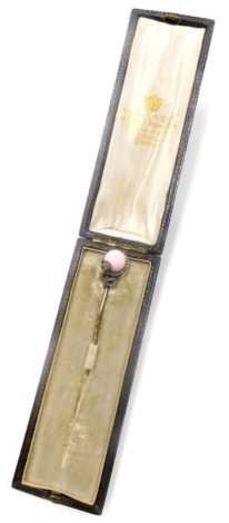 A stick pin, the top formed as a snake holding a pink orb, set with imitation tiny diamonds, on a gold coloured steel pin, in Hobson and Sons of Piccadilly London box, 9cm long, 4.5g all in.