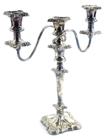 A 20thC silver plated three branch candelabrum, of shaped form with entwined upper stem on a tapering centre, terminating in a scroll and floral lined shaped base, 38cm high.