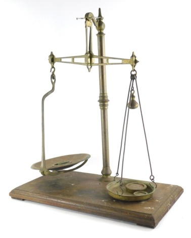 An early 20thC brass table scale, on oak stand with circular pans and associated weights, 53cm wide.