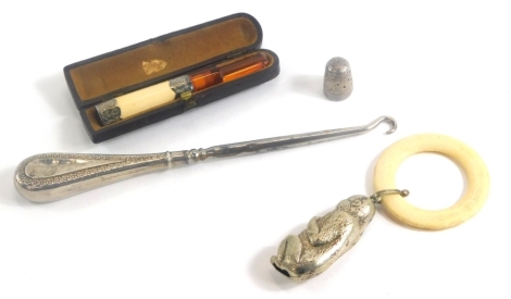 A collection of small silver and silver plated items, comprising a silver thimble, London 1900, a cigarette holder with silver mounts, boxed, a silver handled button hook, and a child's teether, the handle modelled in the form of a monkey holding a piece 