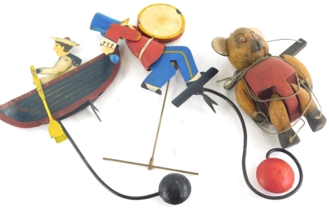 An Edwardian style child's iron weighted boy in boat toy, partially painted, 38cm high, another formed as a drummer, and a treen wooden bear puppet (3).