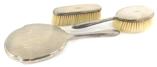 A matched mid 20thC three piece silver back dressing table set, to include two similar Art Deco pieces, hairbrush and clothes brush, 14cm high, with hand mirror, various dates and marks. (3)
