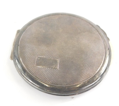 An Elizabeth II silver powder compact, of circular form, partially engine turned with vacant cartouche, fitted interior and thumb mould handle, Birmingham 1969, 6cm diameter.