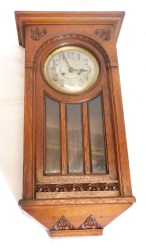 An early 20thC oak cased wall clock, with bevelled glass and silvered dial, 70cm high.