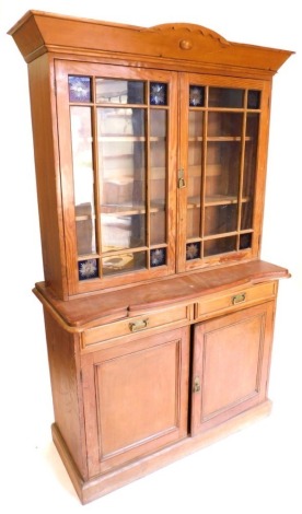 A pine and pitch pine cabinet, the top with a shaped cornice above two glazed doors inset with engraved blue stained glass panels, the base with inverted moulded top above two frieze drawers and two panel doors, on a plinth, part Victorian in origin, 200c