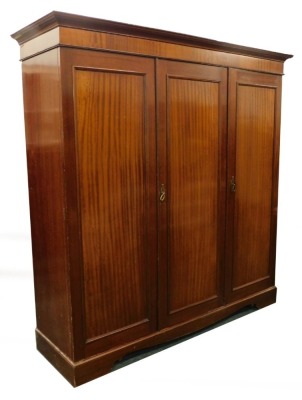 An Edwardian mahogany triple wardrobe, with a moulded cornice and a partly fitted interior, on bracket feet, 198cm high, 190cm wide.