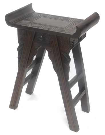 An oriental hardwood stool, the shaped top with carved seat above a small drawer on square section legs with brackets, 52cm wide.