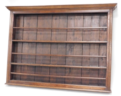 A late 18th/early 19thC oak plate rack, with a moulded cornice above three plate shelves each with a separate rail, flanked by channelled sides, 128cm high, 178cm wide.