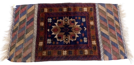 A Belouch rug, with a central medallion, in brown and cream, on a navy ground with multiple borders and flat weave ends, 160cm x 85cm.