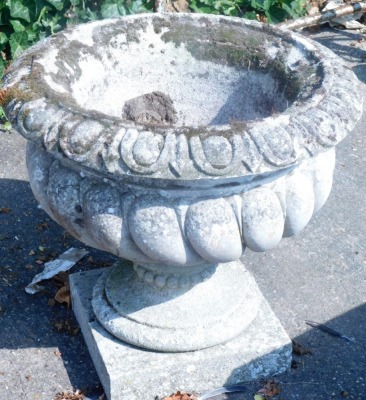 A composition urn, with part fluted decoration on a square base.