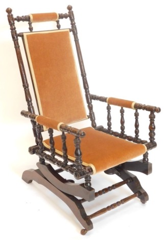 A 19thC turned walnut American type rocking chair, with padded back, armrest and seat.