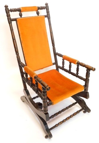 A 19thC turned walnut American style rocking chair, with a padded back, armrest and seat.