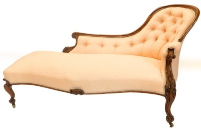 A Victorian rosewood showframe chaise lounge, upholstered in coloured fabric on scroll carved legs, with castors.