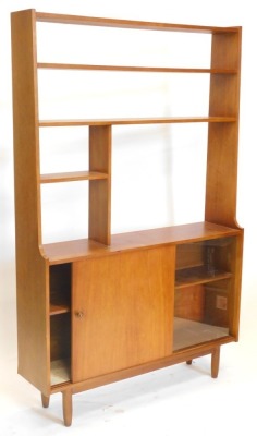 A 1960s/70s teak display unit, with various shelves, glass and a sliding door on turned legs, 167cm high, 106cm wide.