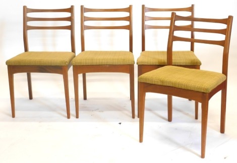 A set of four 1960s/70s teak ladder back dining chairs, each with a padded seat on square tapering legs. The upholstery in this lot does not comply with the 1988 (Fire & Fire Furnishing) Regulations, unless sold to a known exporter or upholsterer it will 