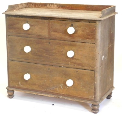 A Victorian pine chest of drawers, with a raised gallery above two short and two long drawers, each with white ceramic handles on bun feet, 98cm wide.