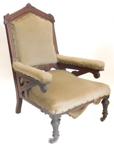 A Victorian gothic open armchair, with an arched back, carved with leaves, etc., on turned legs.