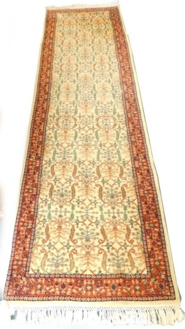 A Persian type runner, with a design of scrolls, flowers, etc., on a cream ground with one wide and two narrow borders, 301cm x 87cm.