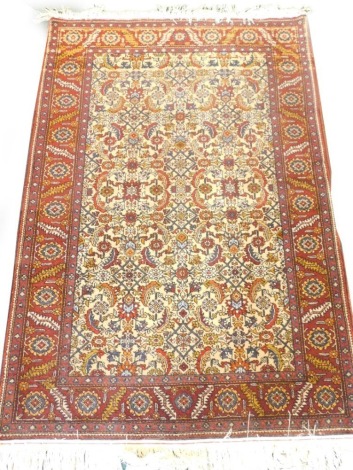 A Persian rug, with an all over design on a cream ground with one wide, two narrow borders, 143cm x 98cm.