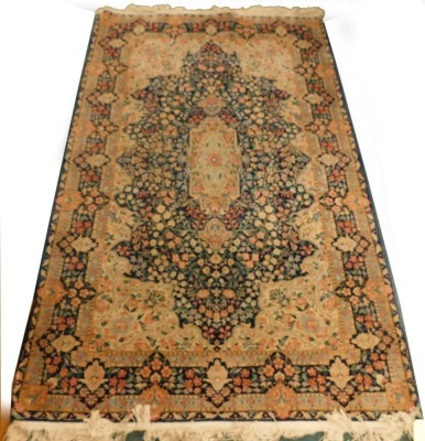 A Persian rug, with a design, decorated with flowers in navy, surrounded by cream and pale blue spandrels, and with multiple borders, 240cm x 152cm.